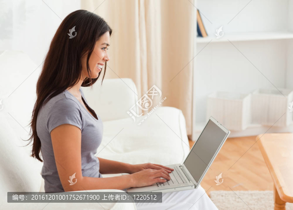 迷人的女人坐在沙發(fā)上與筆記本