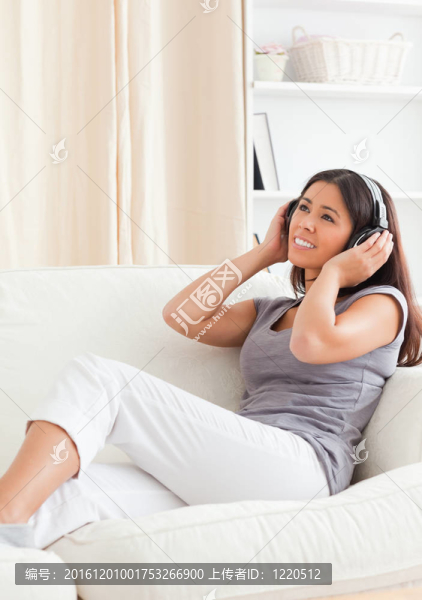 微笑的女人戴著耳機(jī)望著坐在沙發(fā)