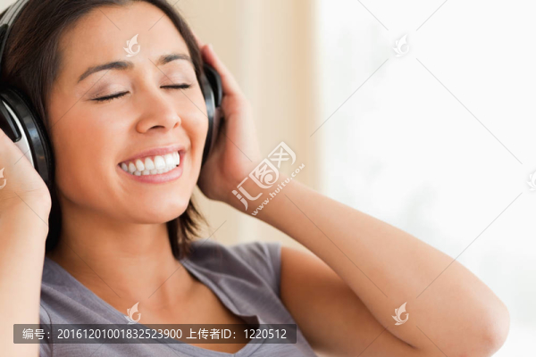 靠近微笑的女人坐在沙發(fā)上，閉著眼睛在客廳用耳機(jī)