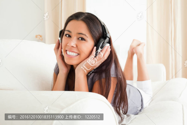 迷人的女人躺在沙發(fā)上看著相機(jī)耳機(jī)