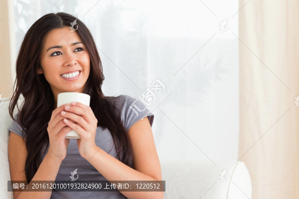微笑的女人拿著杯子看著天花板
