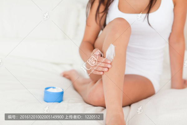 好看的女人把奶油在她的腿上