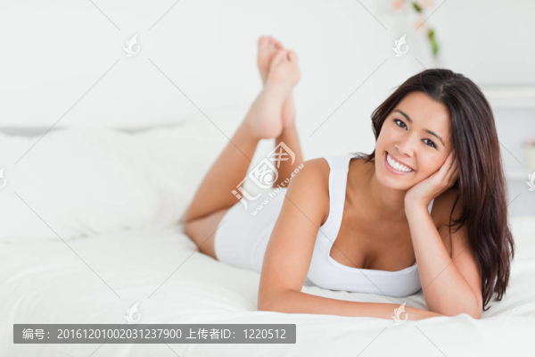 幸福女人躺在床上盤(pán)腿看相機(jī)