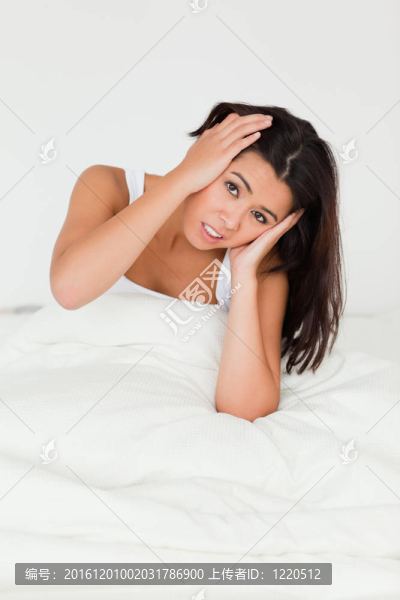 絕望的漂亮的女人坐在床上看著相機在臥室