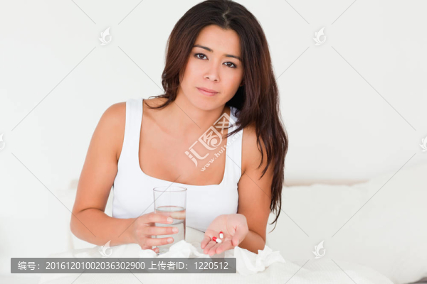 在床上看著相機在臥室吃藥感冒坐的黑發(fā)女人