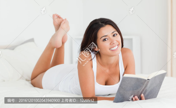 可愛的女人躺在床上看書看著書