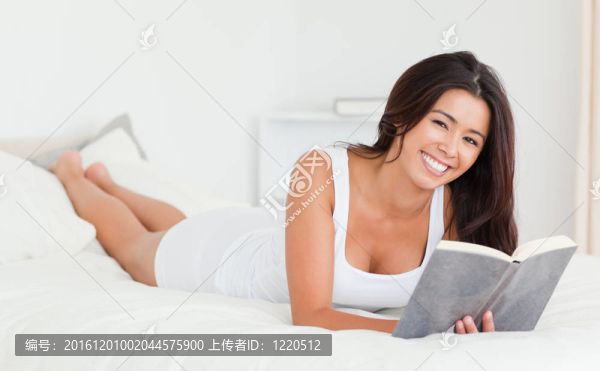 黑發(fā)女子躺在床上看書(shū)