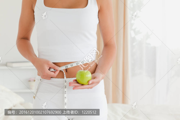 漂亮女人一邊拿著蘋果一邊量著腰
