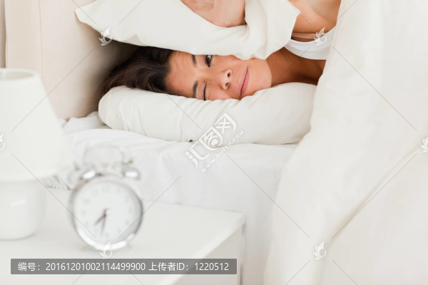睡在床單下的女人不想聽臥室里的鬧鐘