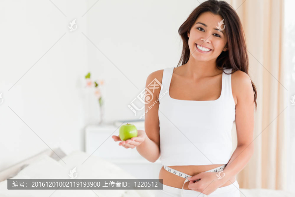 美麗的女人測量她的腰，而持有一個蘋果