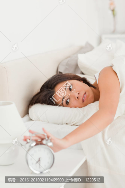 華麗的女人醒來(lái)床單下關(guān)閉鬧鐘
