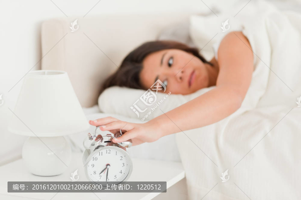 可愛的女人醒來床單下關(guān)閉鬧鐘