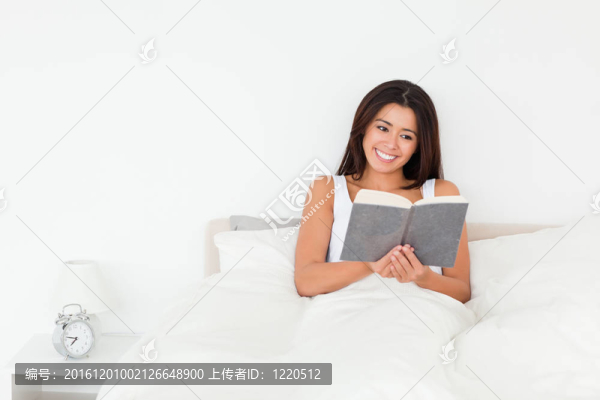 黑發(fā)女子躺在床上看書