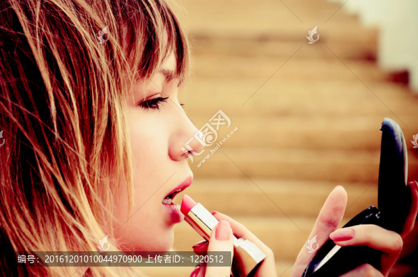 美麗的年輕女子口紅和鏡子