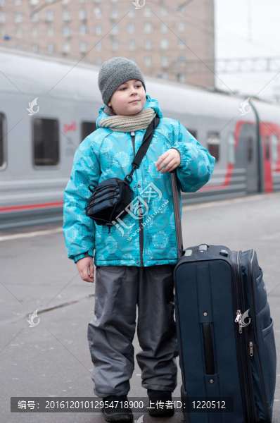 一個(gè)男孩帶著一個(gè)旅行包在火車附近