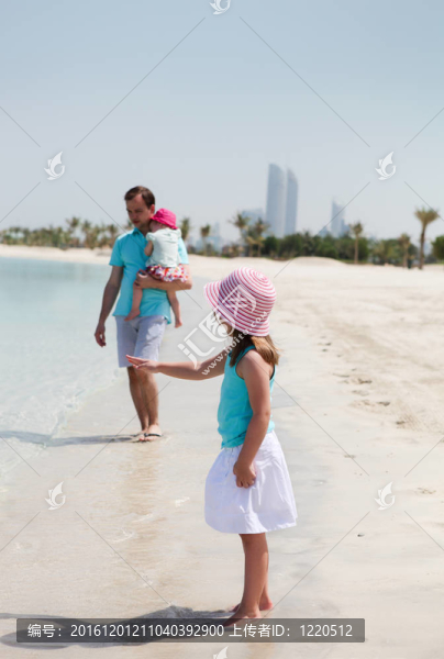 父親和他的兩個女兒在海灘上