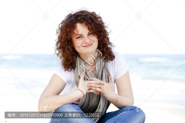 有趣的少女坐在沙灘上的沙灘上。