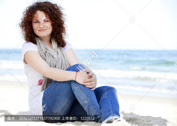 有趣的少女坐在沙灘上的沙灘上。