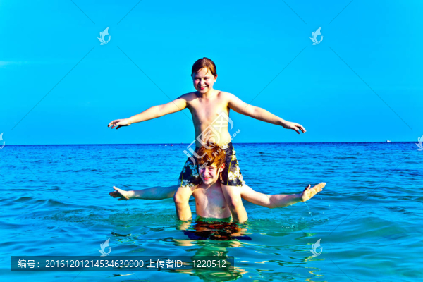 兄弟們正享受著清澈溫暖的水在美麗的海灘和玩子