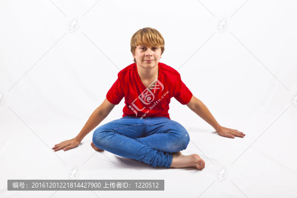 聰明的男孩穿著紅色的襯衫坐在地板上