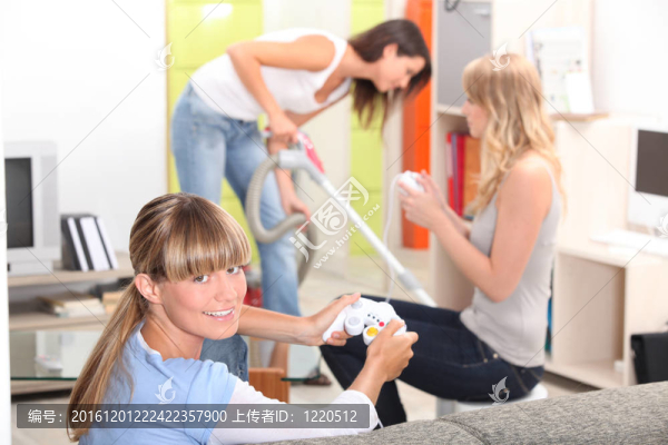 一個女人用吸塵器，兩個女人玩視頻游戲