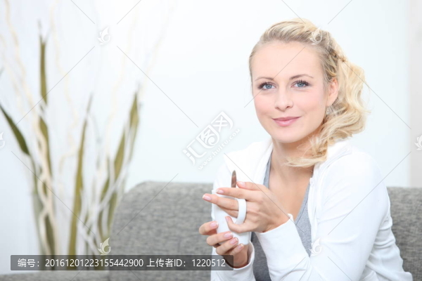 一個(gè)女人在沙發(fā)上喝咖啡。