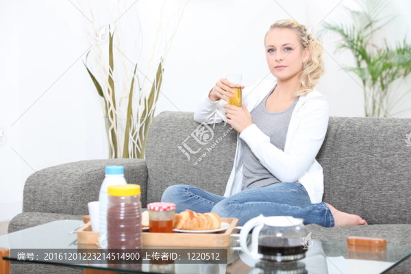 年輕的女人在沙發(fā)上吃早餐