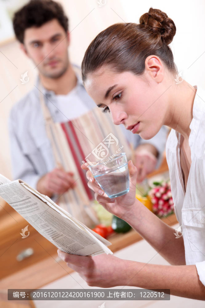 女人喝一杯水，看報紙