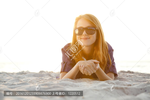 紅頭女孩與耳機(jī)在海灘日出。