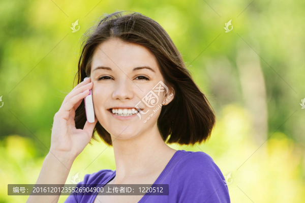 年輕微笑的女人在電話上的肖像