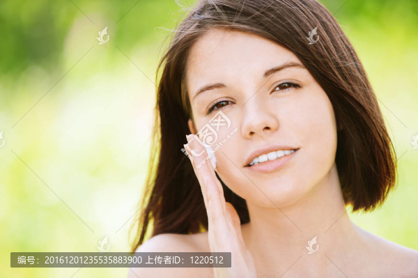年輕漂亮女人在臉上涂奶油的肖像
