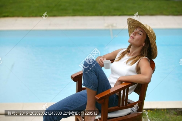 女人坐在泳池邊的草帽
