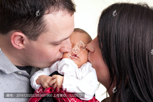 快樂的父母親吻他們的新生嬰兒