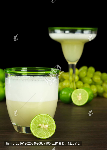 皮斯科酸；秘魯雞尾酒由皮斯科；檸檬汁；糖漿和蛋清加檸檬；背景中的葡萄和另一種雞尾酒（選擇性聚焦；對(duì)前