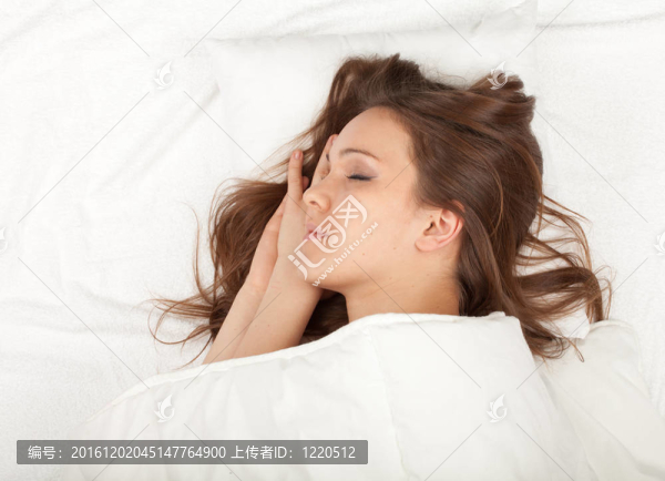美麗的年輕女子睡在白色被褥
