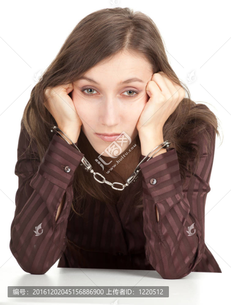 坐在棕色上衣的年輕女子帶著手銬的雙手