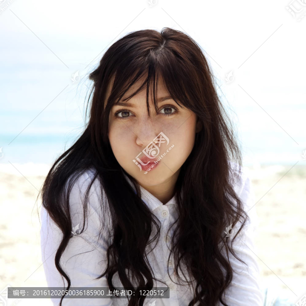 年輕漂亮的黑發(fā)女孩放松在海灘在春天的時候。室外的照片。