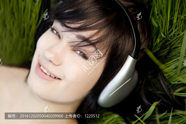 黑發(fā)女孩在綠色的草地上聽音樂。