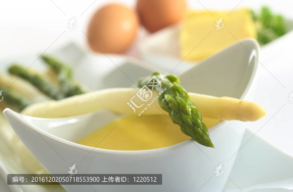 蘆筍躺在滿是荷蘭醬碗（場；很淺的深度對(duì)綠蘆筍頭焦點(diǎn)）