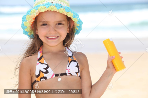 在沙灘上拿著防曬霜的年輕女孩