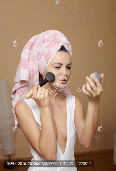 美麗的年輕女子在毛巾頭上化妝后在家里用鏡子洗澡