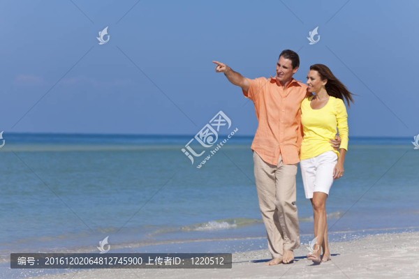 幸福的情侶在海灘上散步和指點