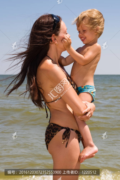 年輕的母親在海邊和她的小兒子玩耍