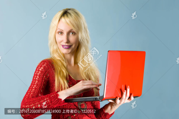 穿著紅色上衣的年輕漂亮的女人和紅色的筆記本電腦