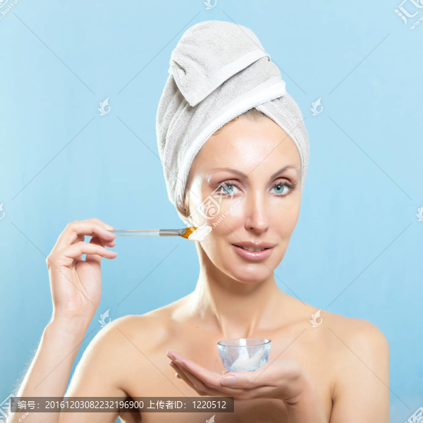 美麗的年輕女子在毛巾與化妝品霜