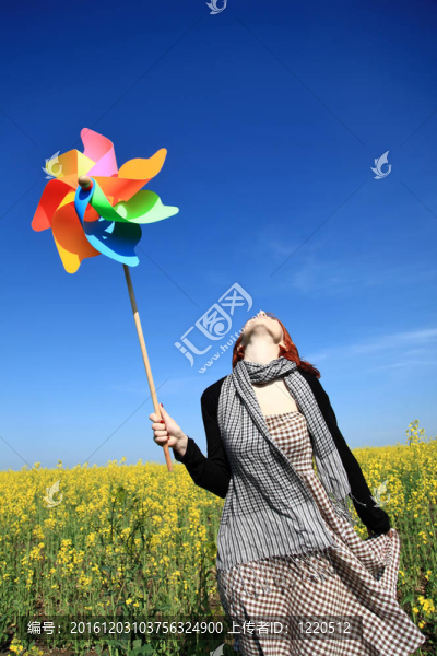油菜田帶風(fēng)力發(fā)電機(jī)的少女。
