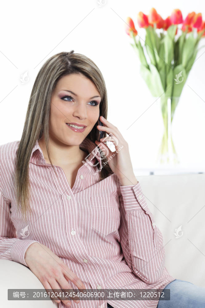 年輕漂亮的女人打電話給在家的沙發(fā)