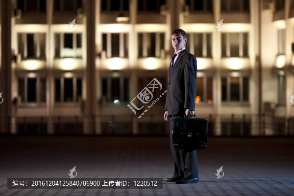 英俊的商人與公文包在夜間城市的背景