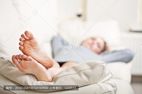 躺在沙發(fā)上的年輕女子；專注于她的腳