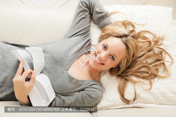 快樂的年輕女人躺在書